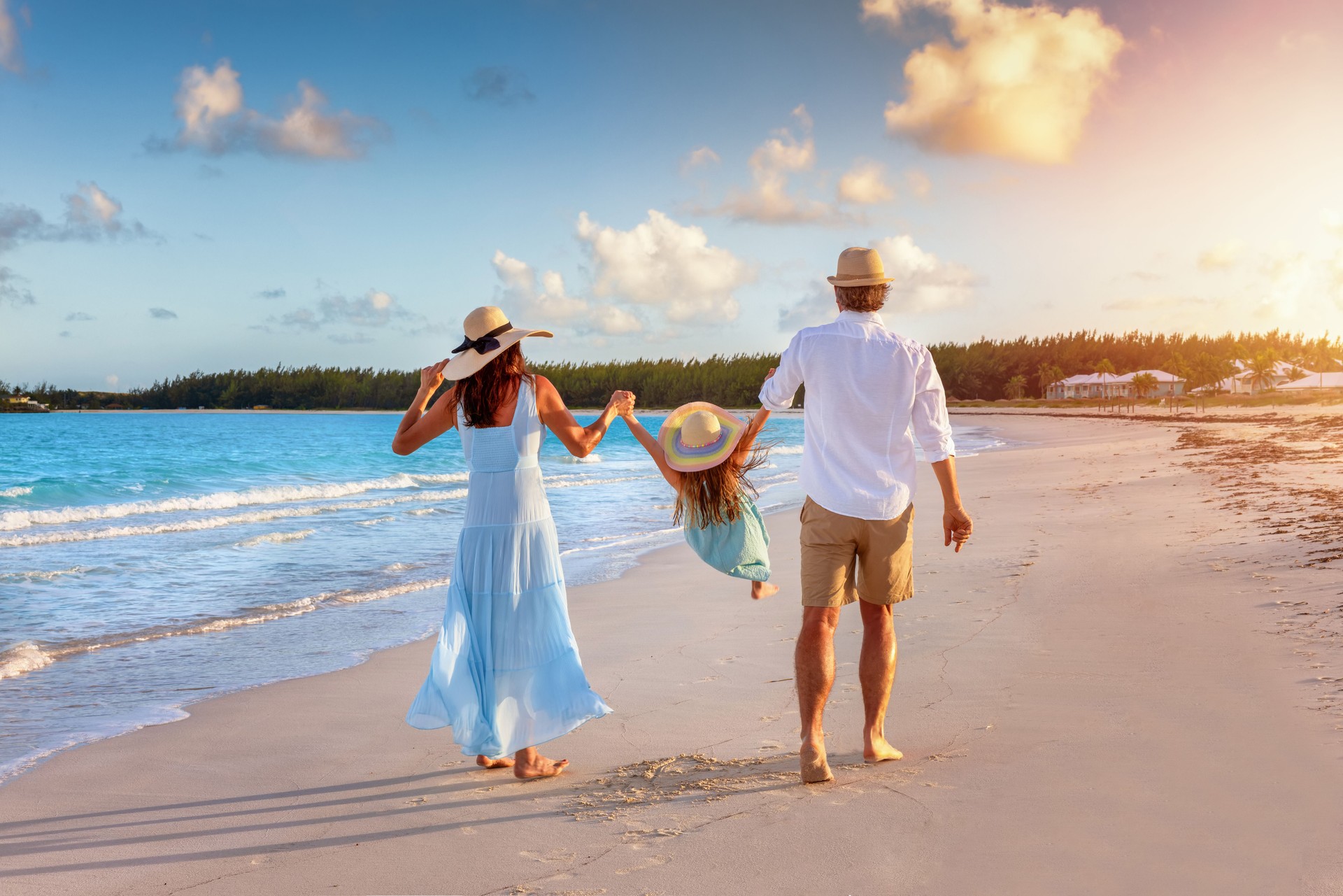 A happy family in walks hand in hand down a tropical beach during sunset time